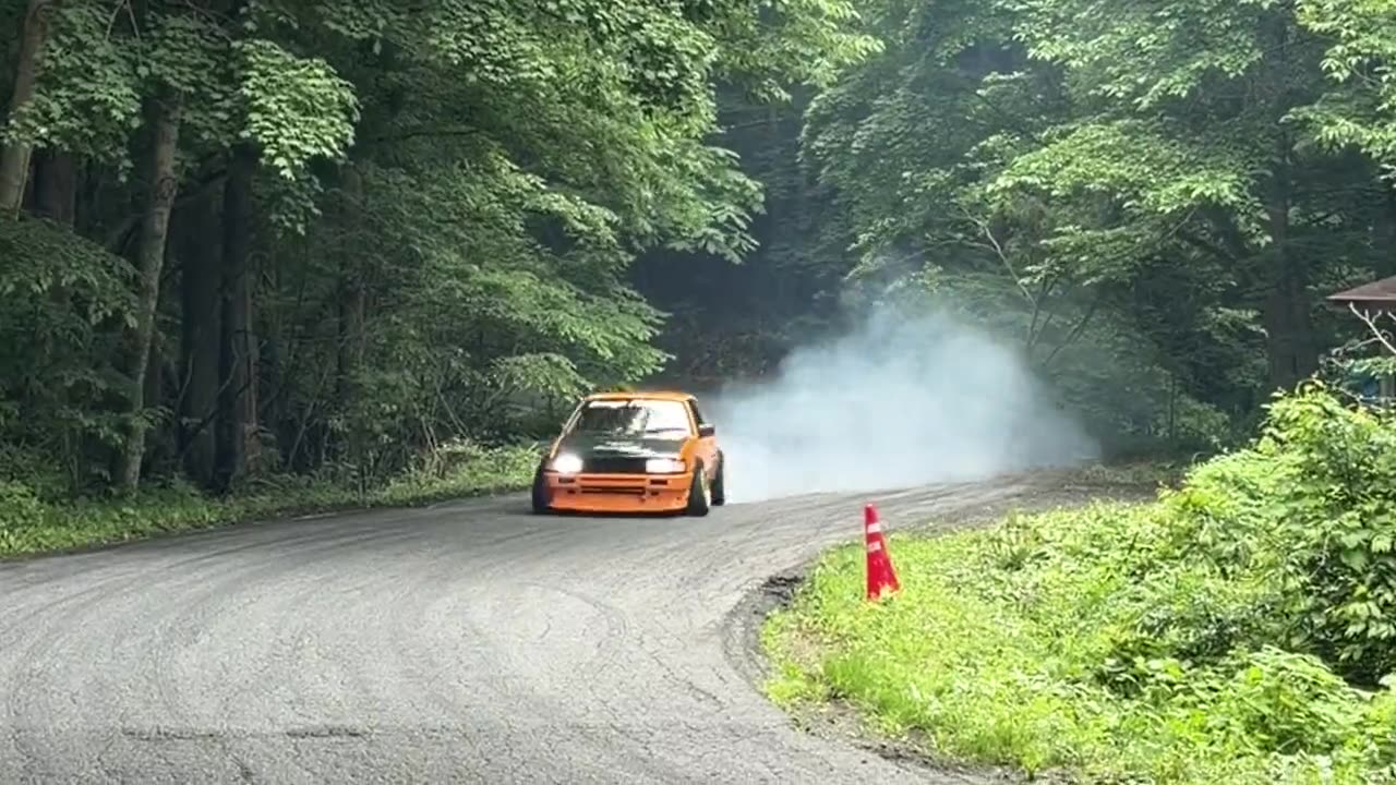 Modified AE86 sliding through a hairpin on a touge course