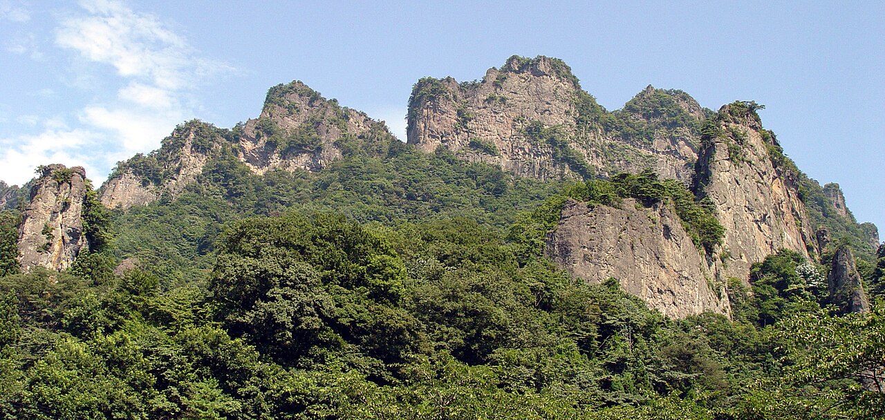 Jagged rock peaks of Mt Myogi rising above green forest in summer